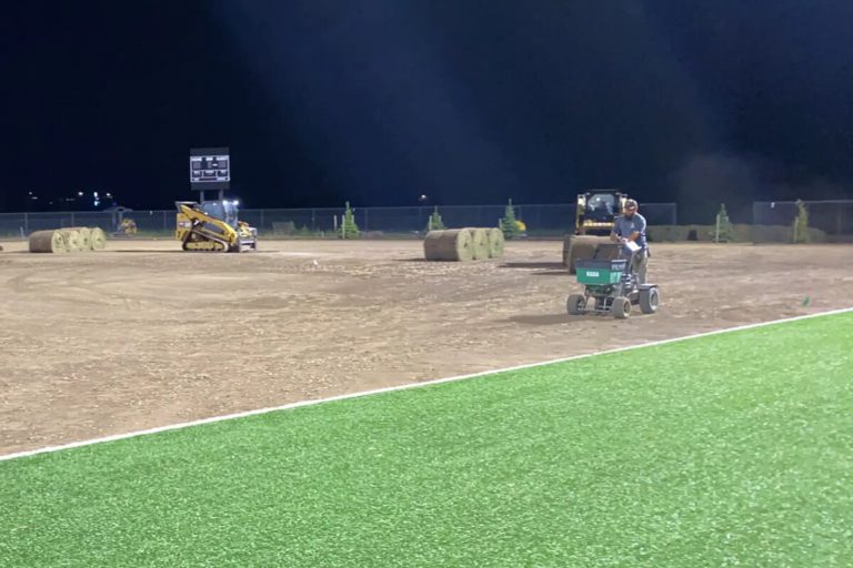 Ball field with artificial turf in the foreground and sod in the background.