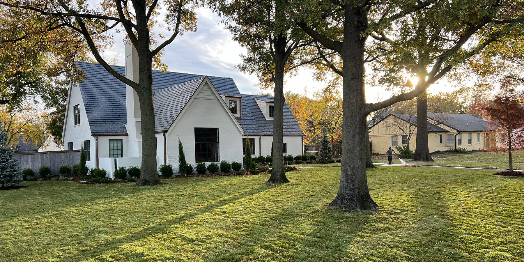 Front elevation of white brick home with beautiful landscaping.