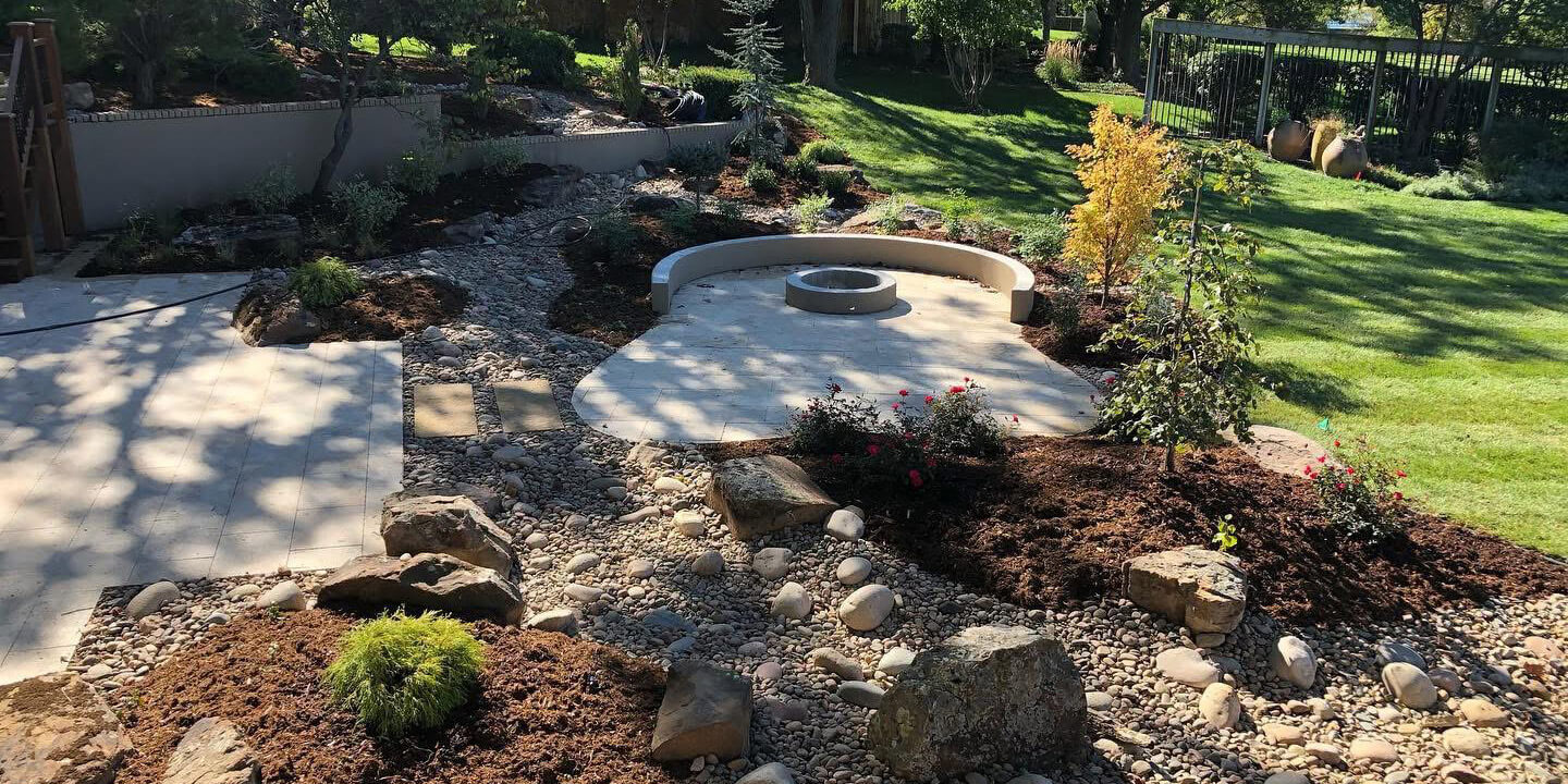 A stone fire pit with landscaping.