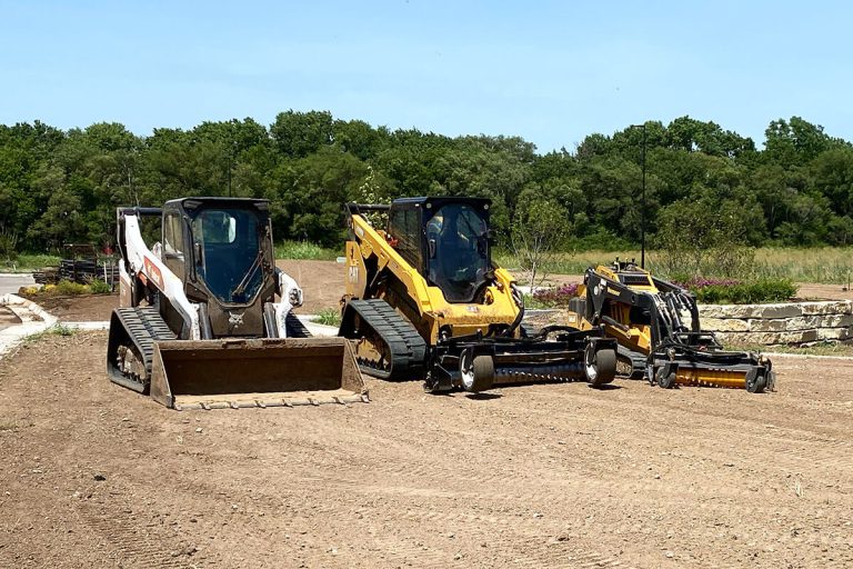 Freshly leveled dirt with machinery in the background.
