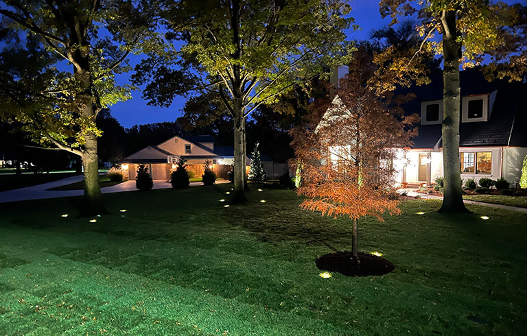 Exterior of a home at night with landscape lighting.