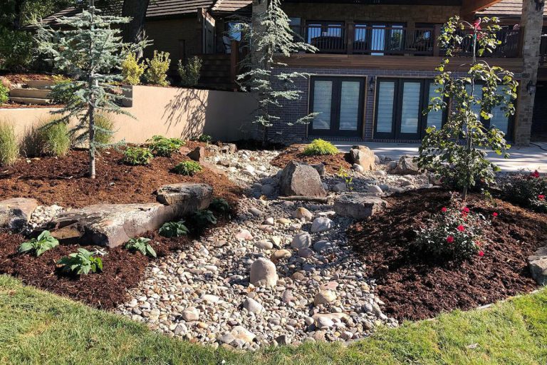 A beautifully landscaped residential garden including plants, rocks and mulch.