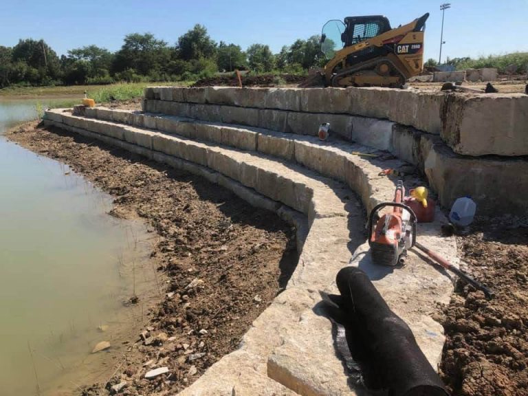 A stone retaining wall next to a retention pond.