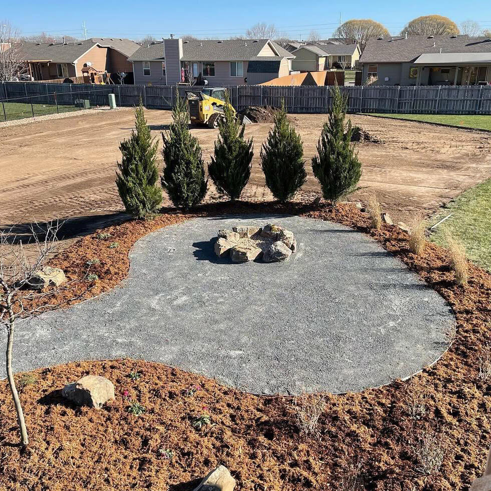 Five evergreen trees next to a fire pit.